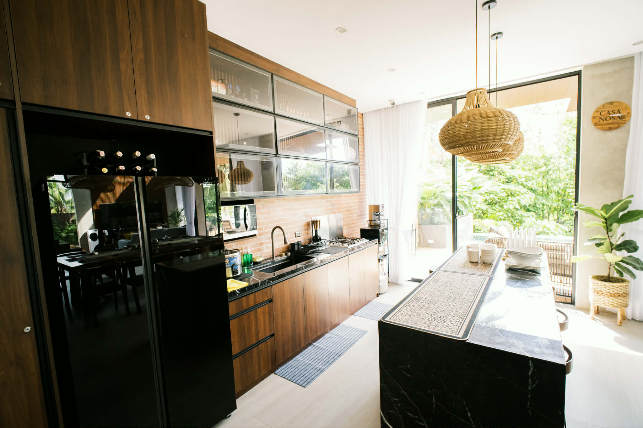 Fully equipped kitchen with black marble island and rattan pendant lights