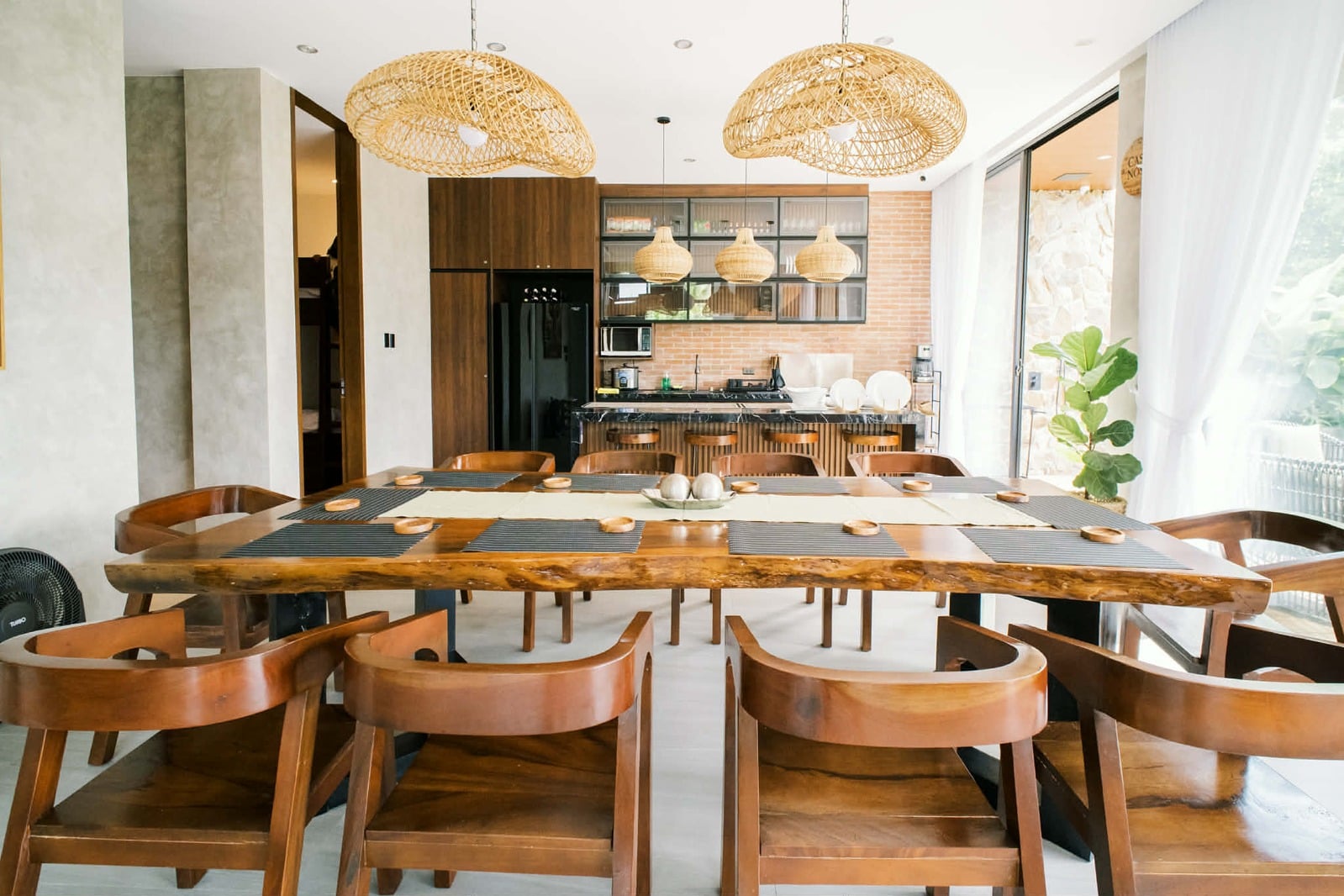 Live-edge dining table set for twelve beneath rattan pendants