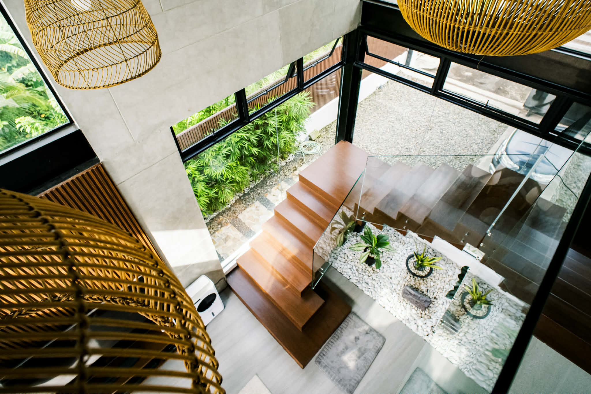 Floating hardwood staircase over a pebble garden, seen from the mezzanine