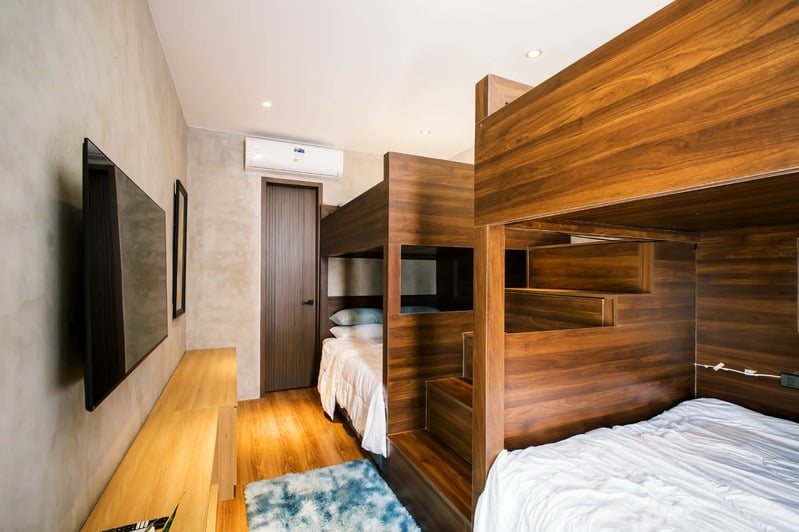 Room 3 — bunk beds with wall-mounted smart TV and warm timber finishes